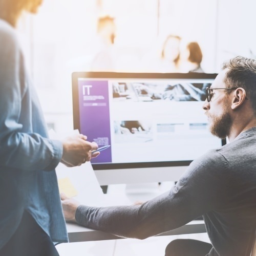 nonSAP Migration Frau und Mann unterhalten sich an einem Schreibtisch mit Monitor